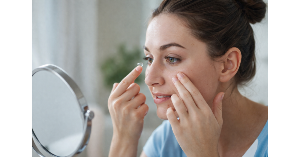 Person carefully inserting a contact lens after proper hand hygiene to maintain safe contact lens habits and healthy eyes.