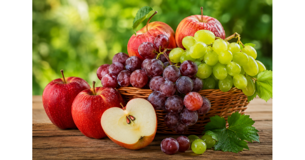 Healthy apples and red and green grapes in a basket on a wooden table with a fresh natural background